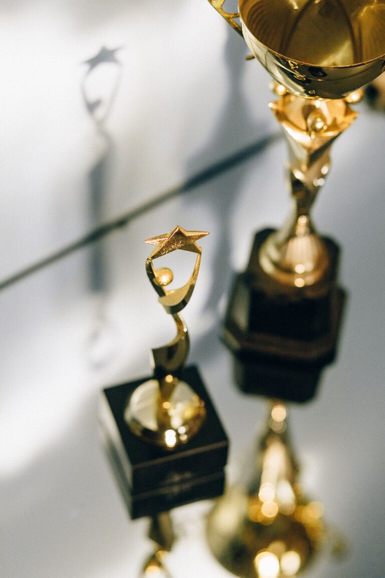 Close-up of shiny golden star trophies reflecting on a glass surface