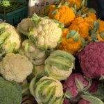 Variety of colorful cauliflower heads displayed at a market