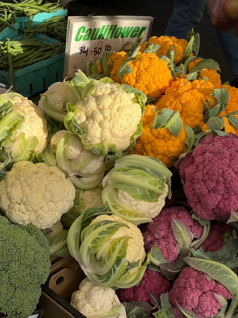 Variety of colorful cauliflower heads displayed at a market