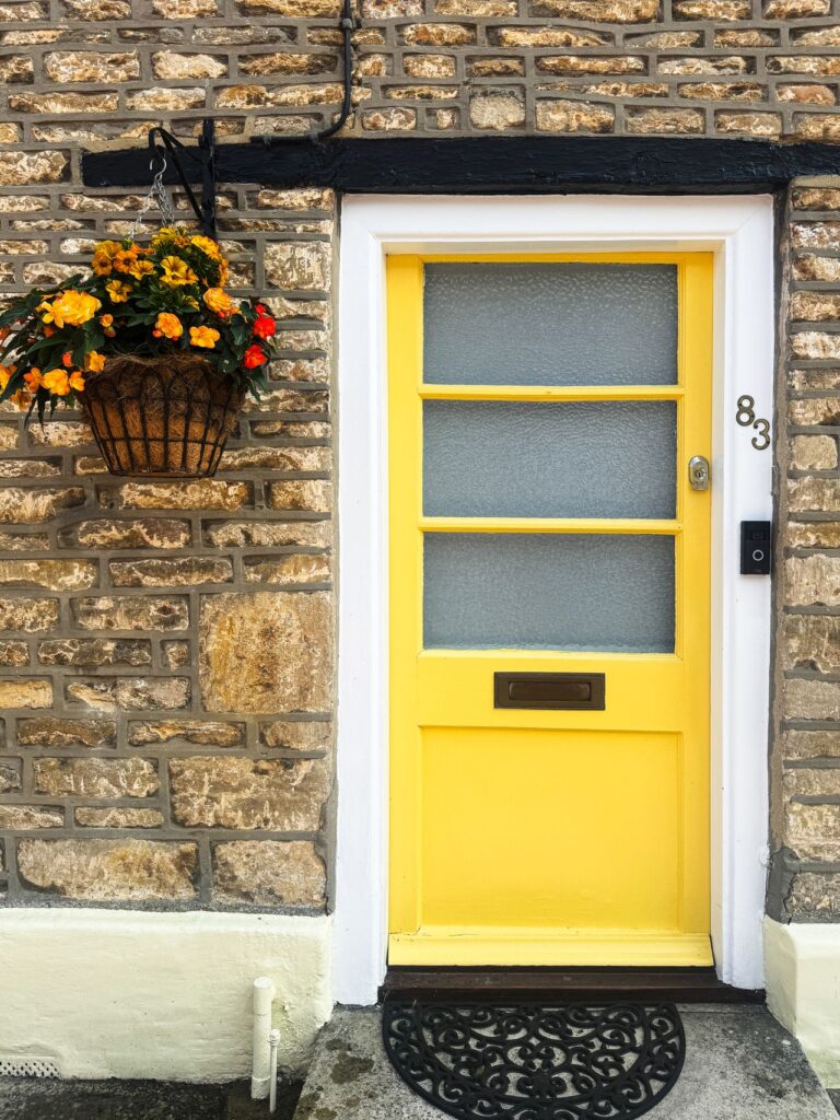 A vibrant yellow door with flowers in Cricklade, England
